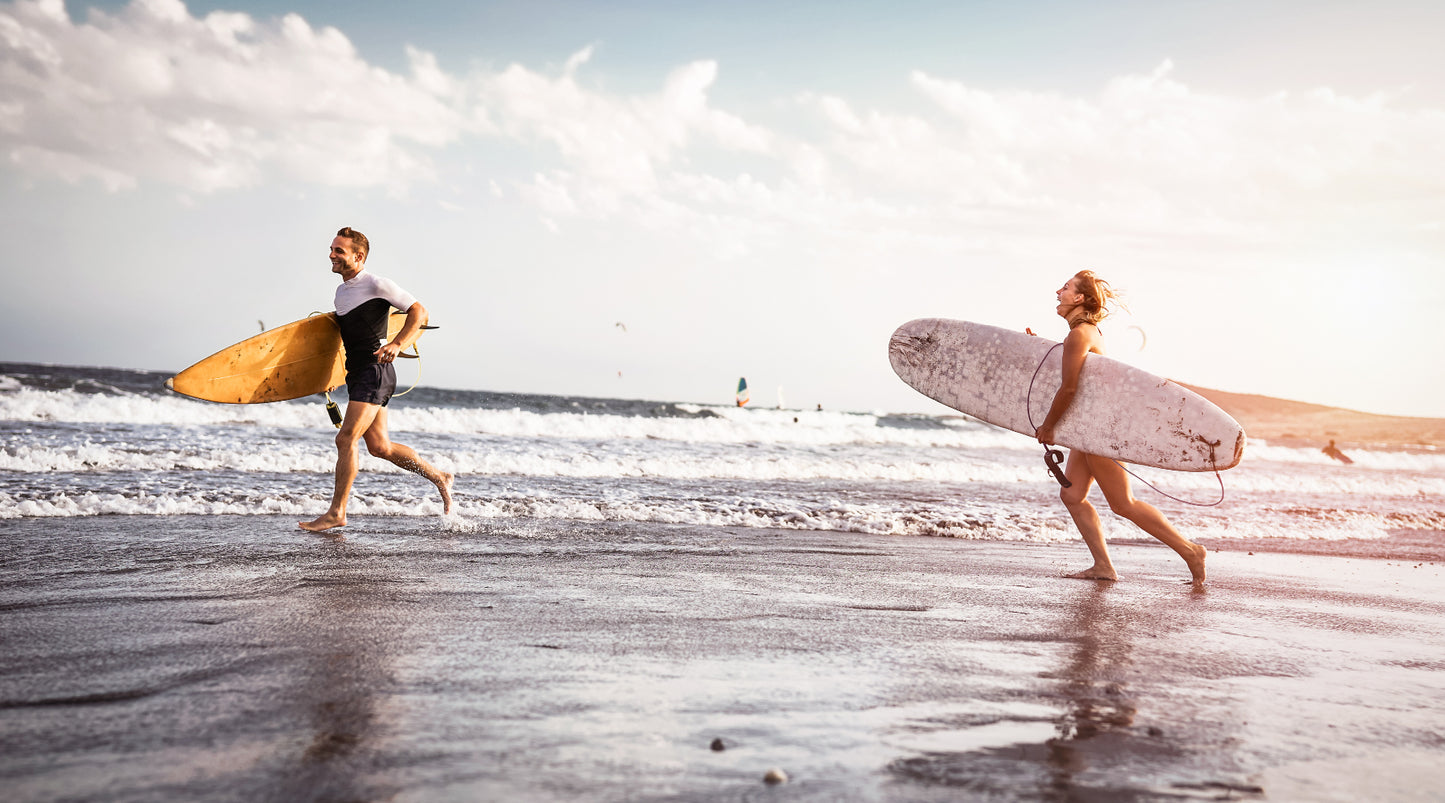 Two surfers running into the surf